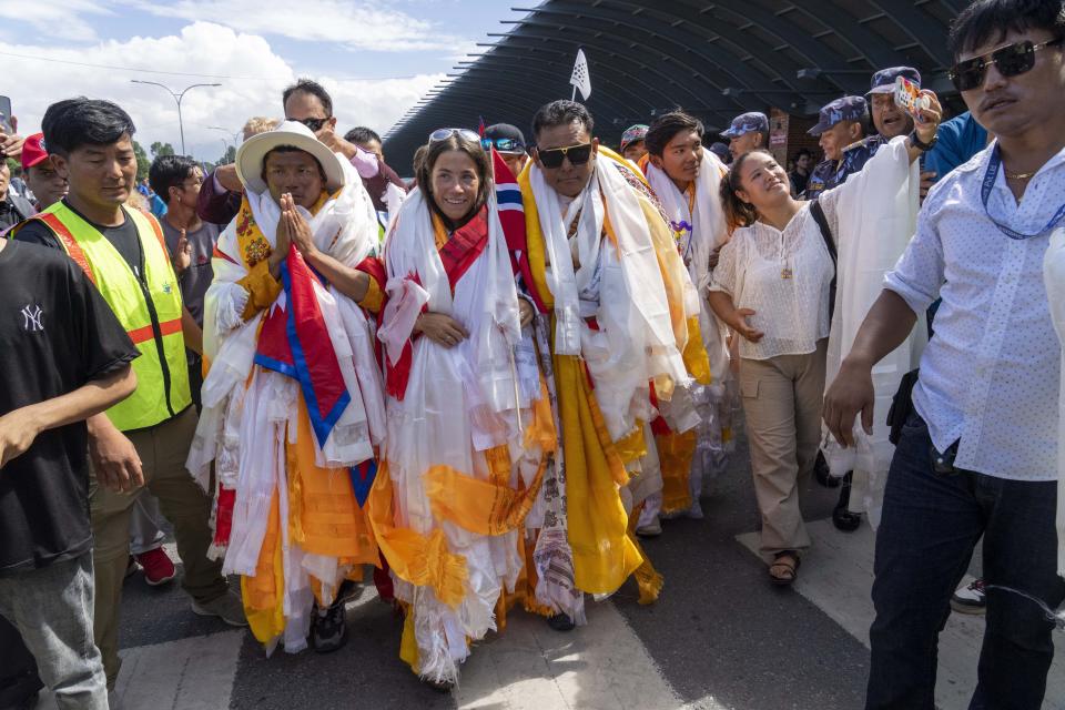 Norwegian woman mountain climber Kristin Harila, center and her Nepali Sherpa guide Tenjen Sherpa, left, who on Thursday set a new record by scaling the world's 14 highest peaks in 92 days arrive at the airport in Kathmandu, Nepal, Saturday, Aug.5, 2023. (AP Photo/Niranjan Shreshta)