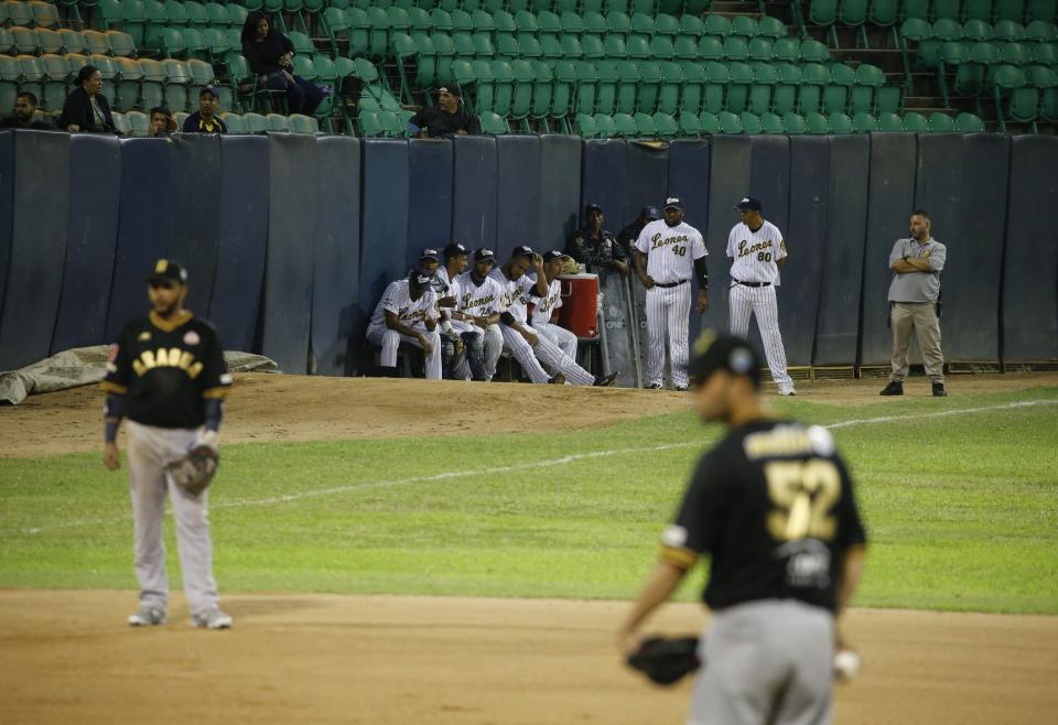 Leones de Caracas players watch the opening winter season baseball game against Tigres de Aragua in Caracas, Venezuela, Tuesday, Nov. 5, 2019. Tough times have shortened the season by a third of its games and it started weeks late. (AP Photo/Ariana Cubillos)