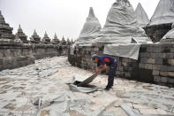 A worker spreads plastic sheets to cover Borobudur temple to protect from volcanic ash, from an eruption of Mount Kelud, in Magelang, central Java, Indonesia, Friday, Feb. 14, 2014. An explosive volcanic eruption on Indonesia's most populous island blasted ash and debris 18 kilometers (12 miles) into the air Friday, killing two people while forcing authorities to evacuate more than 100,000 and close six airports. (AP Photo/Slamet Riyadi)