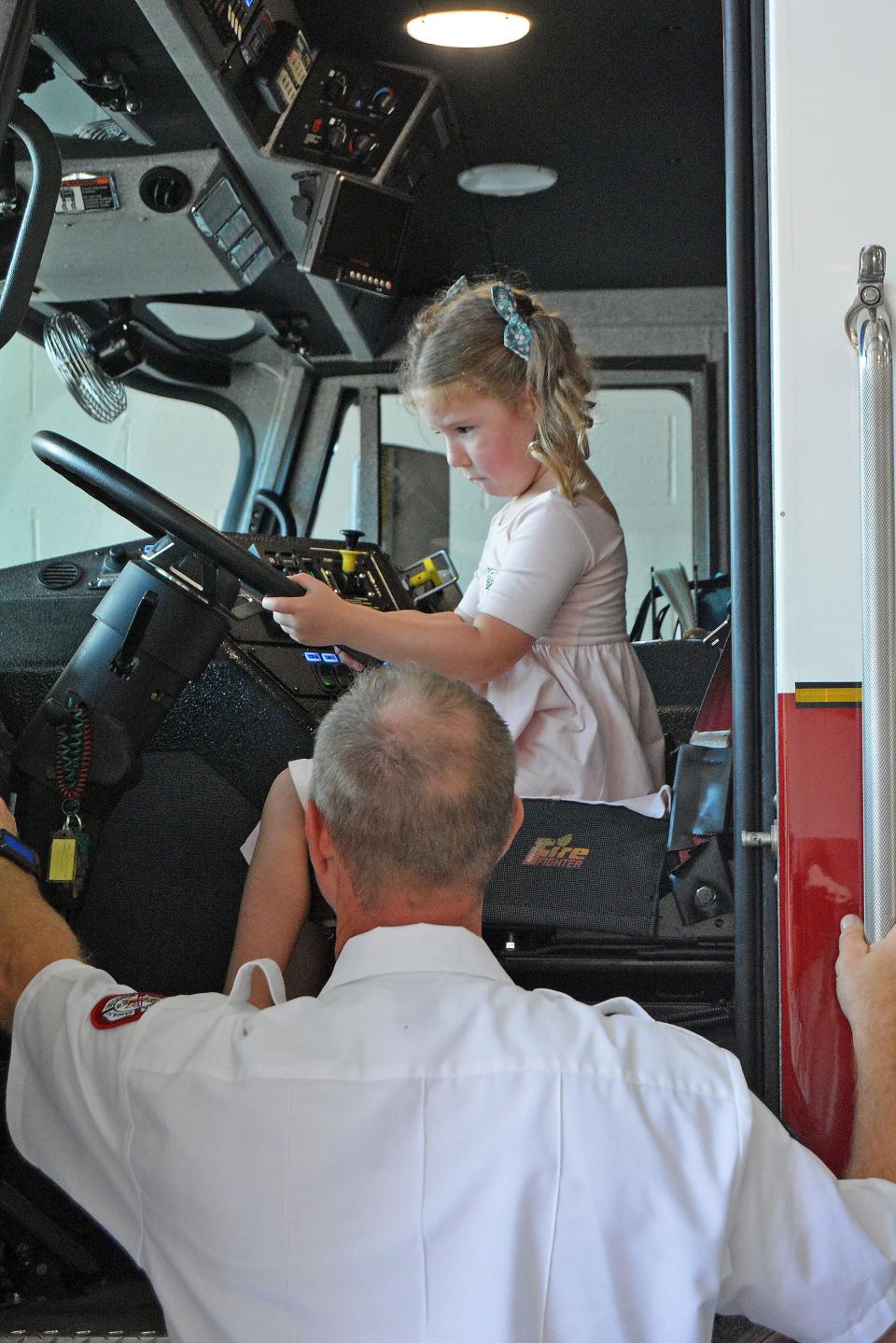 Columbia Fire Department Captain Brian Strong explains all the buttons in a fire truck to Mabry Spainhour, 4, while her mom, Marissa, not pictured, watches.