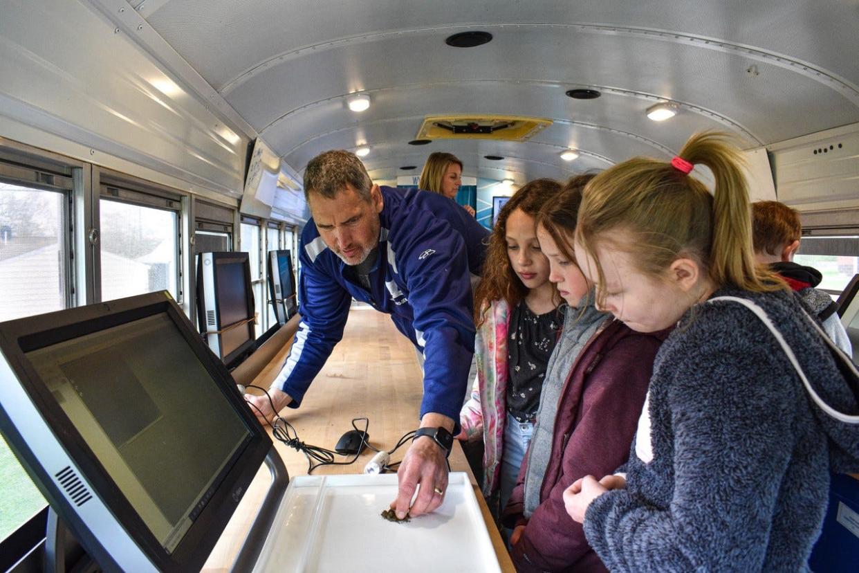 Bryan Zimmerman, Vanguard-Sentinel director of operations, drops a soil sample on the microscope tray for, from left, Xayla Grine, Laila Long and Phenix McCreery.