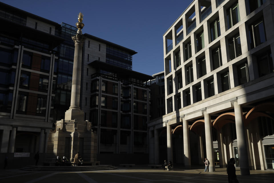 People sit, stand and pass through Paternoster Square in the City of London financial district of London, Friday, Jan. 22, 2021, during England's third national lockdown since the coronavirus outbreak began. The U.K. is under an indefinite national lockdown to curb the spread of the new variant, with nonessential shops, gyms and hairdressers closed, most people working from home and schools largely offering remote learning. (AP Photo/Matt Dunham)