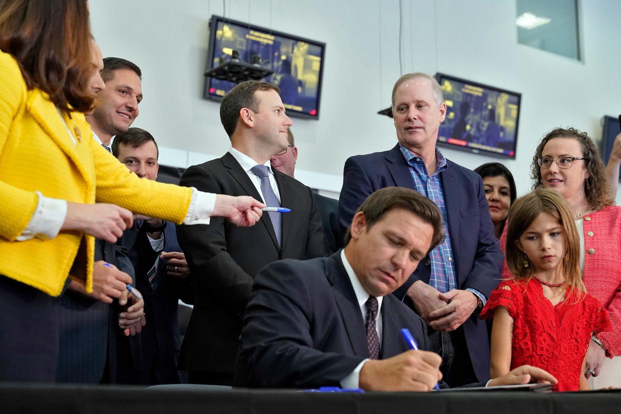 Gov. Ron DeSantis, seated, signs a bill in front of supporters and members of the media during a news conference Nov. 18 in Brandon. DeSantis signed legislation putting new limits on coronavirus vaccine and mask mandates.