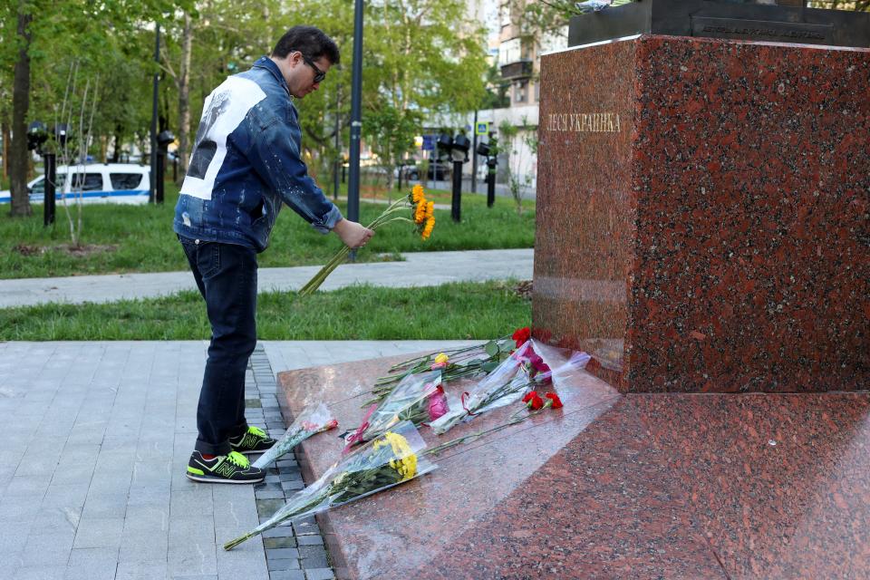 A man lays flowers at a monument to Ukrainian poet Lesya Ukrainka (REUTERS)