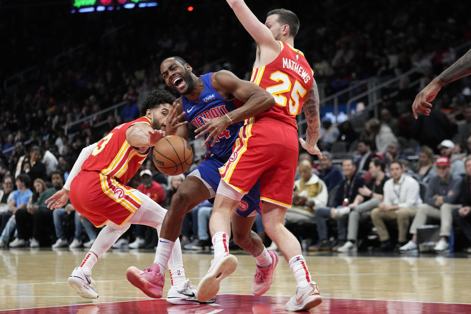 Detroit Pistons guard Alec Burks (14) is fouled as he tries to drive between Atlanta Hawks guards Seth Lundy (3) and Garrison Mathews (25) during the first half of an NBA basketball game Monday, Dec. 18, 2023, in Atlanta. (AP Photo/John Bazemore)y