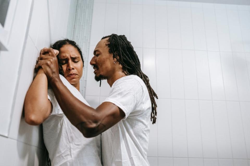 Black man pinning a Black woman against the wall