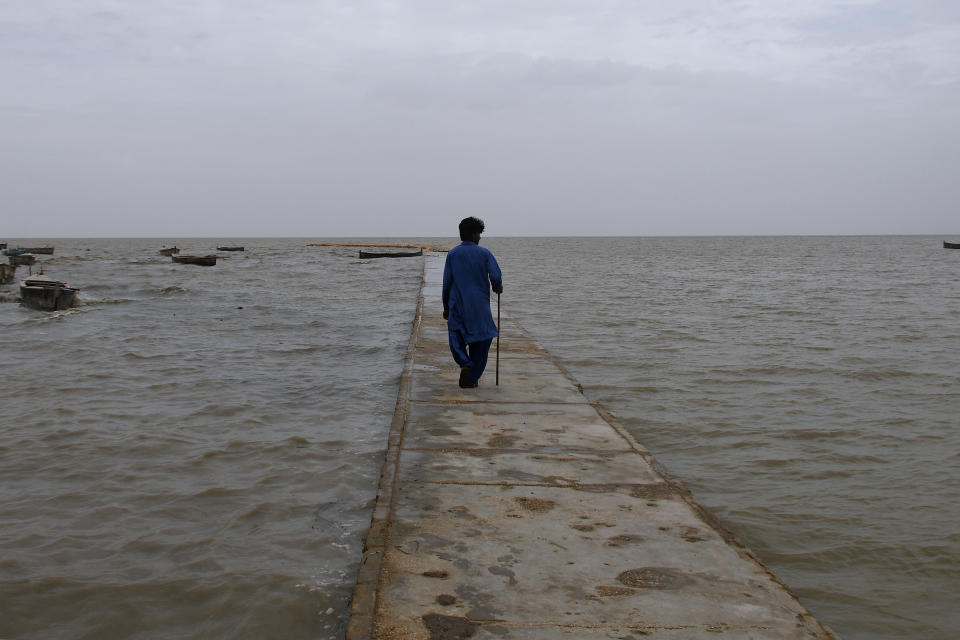 A man walks on a floating pathway on a Sea coast, which looks empty after people evacuated due to Cyclone Biparjoy approaching, in Golarchi near Badin, Pakistan's southern district in the Sindh province, Wednesday, June 14, 2023. The coastal regions of India and Pakistan were on high alert Wednesday with tens of thousands being evacuated a day before Cyclone Biparjoy was expected to make landfall. (AP Photo/Umair Rajput)