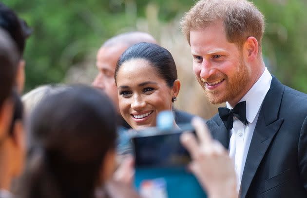 A fan snaps a photo of Meghan and Harry at the London premiere of