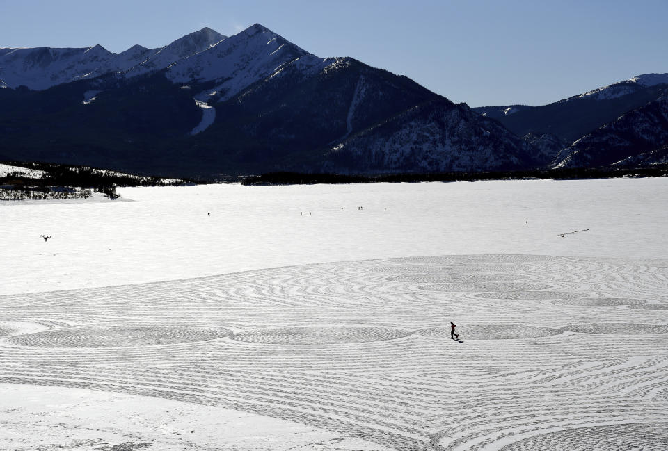 In this photo taken Jan. 7, 2020, British artist Simon Beck uses snowshoes to create a massive geometrical design on a frozen reservoir near Silverthorne, Colo. Using a compass, snowshoes and his background as a cartographer and competitive orienteer, the 61-year-old snow artist and a handful of volunteers recently spent 12 hours tromping across the frozen reservoir in the resort town west of Denver, to create a spectacular geometrical design on a fresh canvas of snow. (AP Photo/Thomas Peipert)