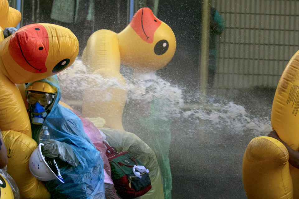 Pro-democracy protesters take cover with inflatable ducks as police fire water cannons during an anti-government rally near the Parliament in Bangkok, Tuesday, Nov. 17, 2020. Thailand's political battleground shifted to the country's Parliament Tuesday, where lawmakers are considering proposals to amend the country's constitution, one of the core demands of the student-led pro-democracy movement. (AP Photo/Wason Wanichakorn)