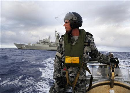 Standing in a rigid hull inflatable boat launched from the Australian Navy ship HMAS Perth, Leading Seaman, Boatswain's Mate, William Sharkey searches for possible debris in the southern Indian Ocean in the continuing search for the missing Malaysian Airlines flight MH370 in this picture released by the Australian Defence Force April 17, 2014. REUTERS/Australian Defence Force/Handout via Reuters