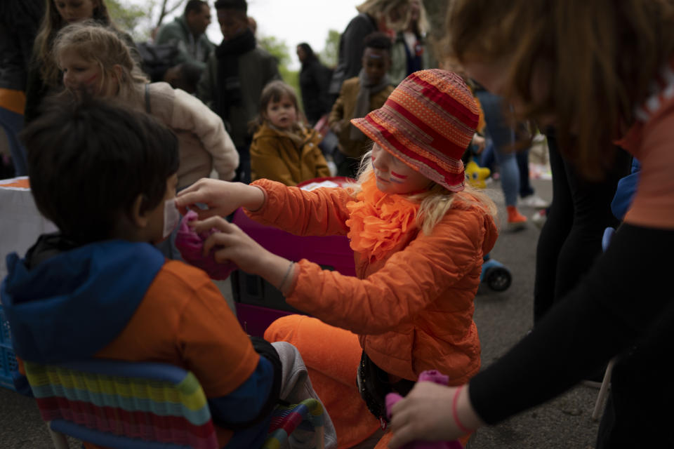 Orange-clad children decorate faces of other children during King's Day celebrations in Amsterdam, Netherlands, Wednesday, April 27, 2022. After two years of celebrations muted by coronavirus lockdowns, the Netherlands marked the 55th anniversary of King Willem-Alexander of the House of Orange with street parties, music festivals and a national poll showing trust in the monarch ebbing away. (AP Photo/Peter Dejong)