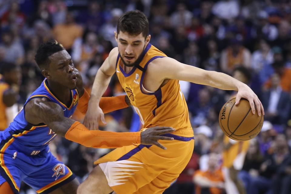 Oklahoma City Thunder guard Dennis Schroeder, left, reaches in to attempt a steal from Phoenix Suns guard Ty Jerome during the first half of an NBA basketball game Friday, Jan. 31, 2020, in Phoenix. (AP Photo/Ross D. Franklin)