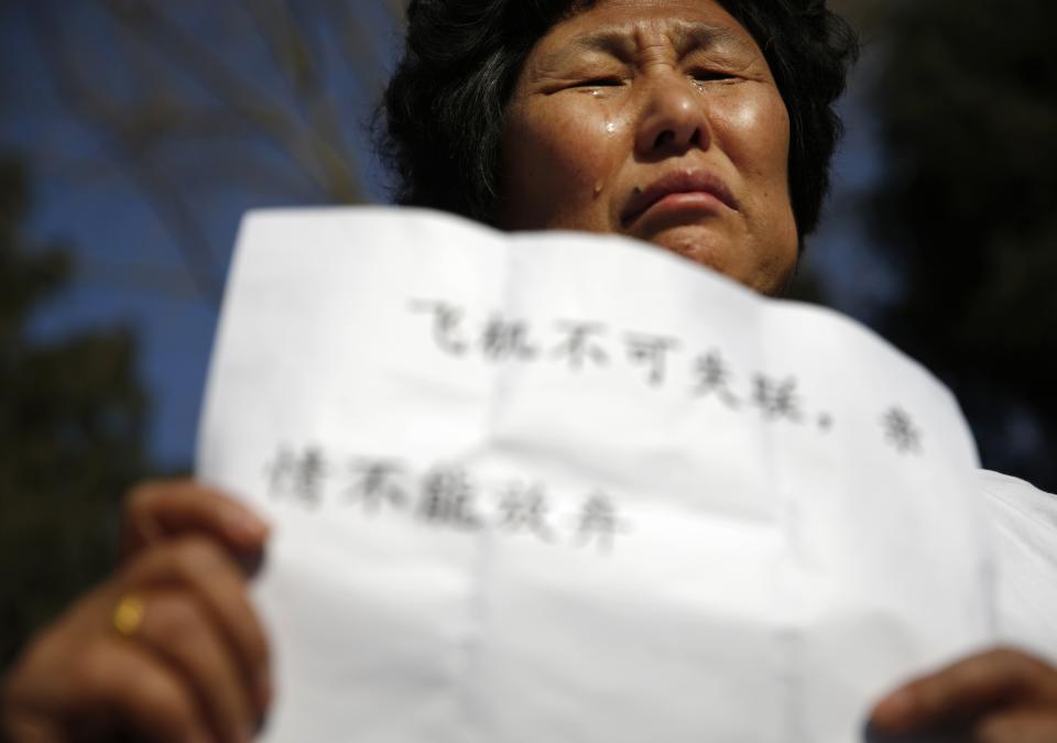 Liu cries as she holds a sign during a gathering of family members of the missing passengers outside the Malaysian embassy in Beijing