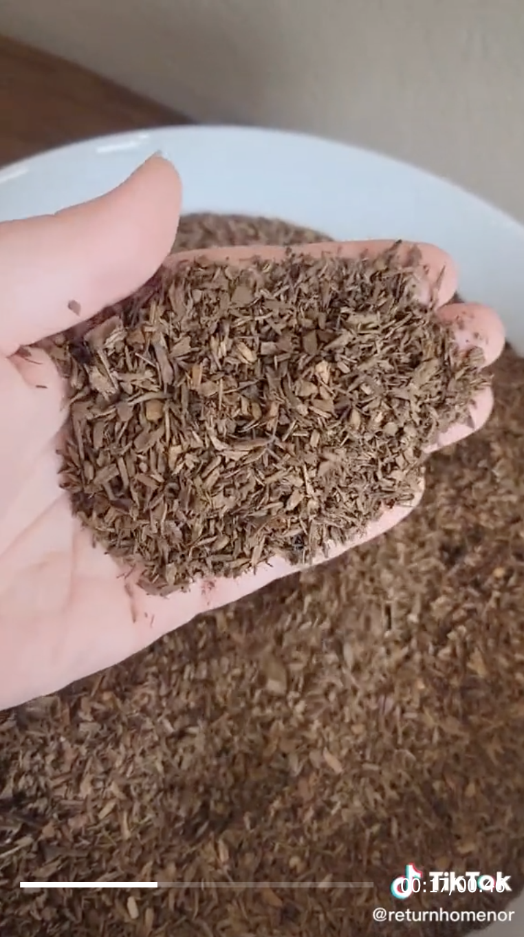 An image from Return Home's TikTok that shows a hand holding compost chips
