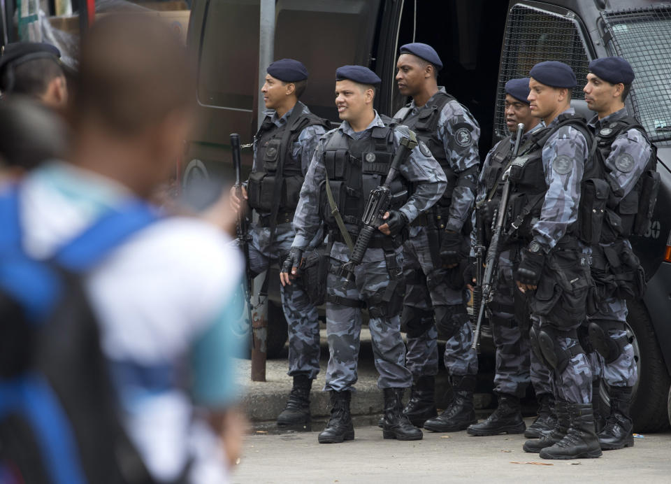 Police officers stand guard at the Rocinha slum in Rio de Janeiro, Brazil, Monday, Feb.17, 2014. Police in Rio de Janeiro are reinforcing patrols in the Brazilian city's biggest slum after a weekend of shootouts. Rocinha is among Rio's "pacified" slums. In 2011, police entered and pushed the ruling drug gang out, and set up a permanent post. The slum pacification program is a key element of Rio's security plans ahead of this year's World Cup and the 2016 Olympics. (AP Photo/Silvia Izquierdo)