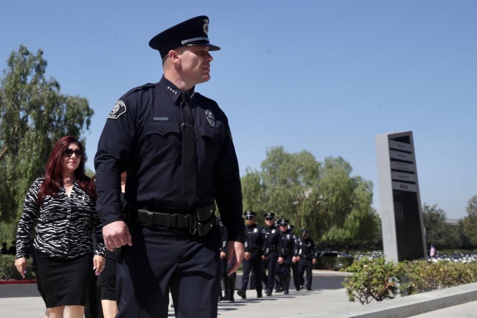 A police chief walks in front of a line of officers