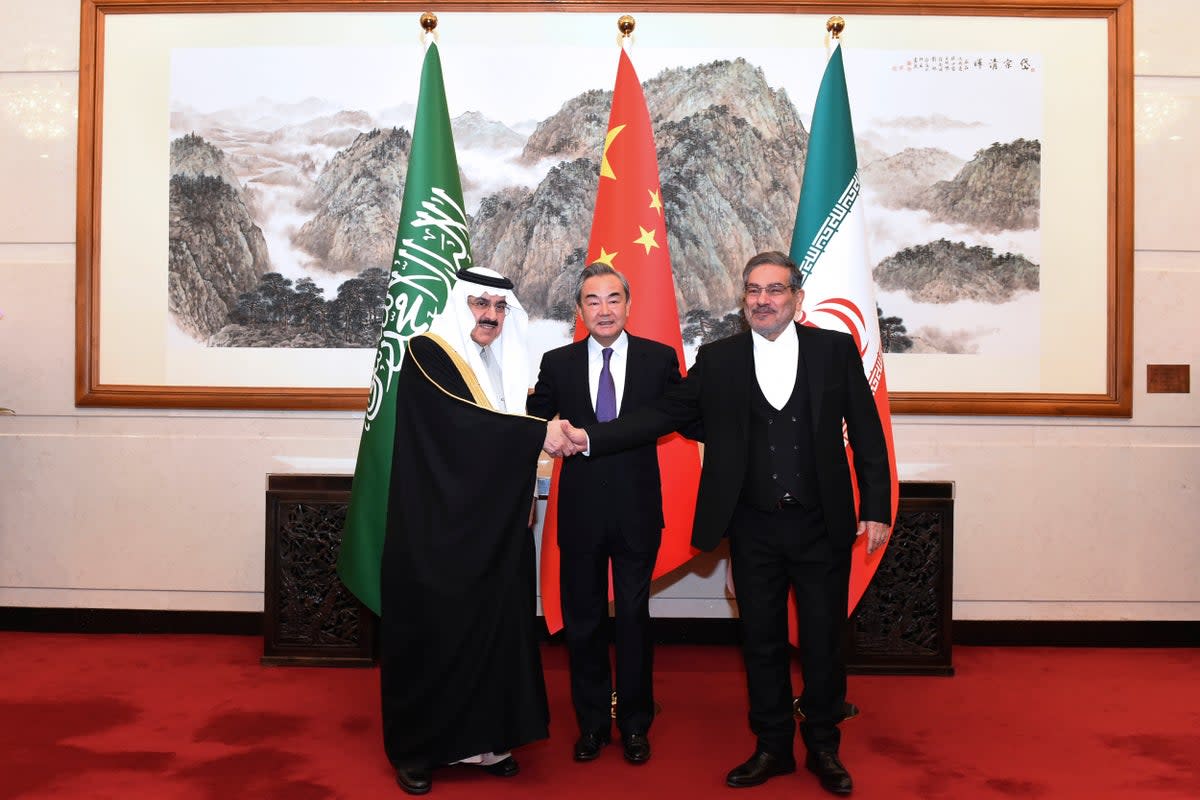 Ali Shamkhani, the secretary of Iran's Supreme National Security Council, right, shakes hands with Saudi national security adviser Musaad bin Mohammed al-Aiban, left, as Wang Yi, China's most senior diplomat, looks on (Xinhua/AP)