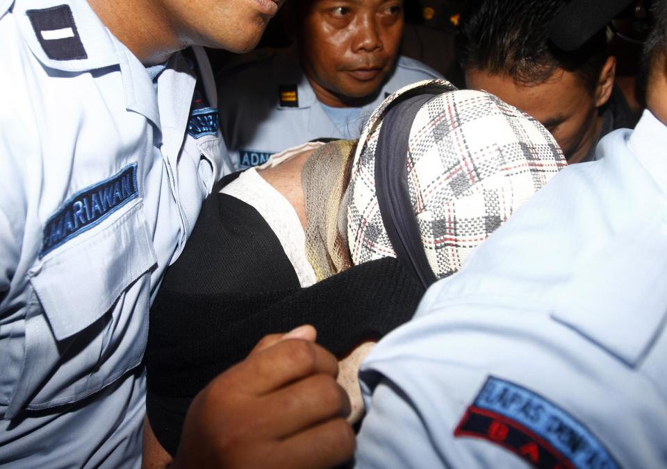 Australian Schapelle Corby, center, is escorted by prison guards to the prosecutor office after she received her parole in Bali, Indonesia, Monday, Feb. 10, 2014. The Australian woman convicted of smuggling marijuana into Indonesia in 2005 has been released from jail on parole. (AP Photo/Firdia Lisnawati)