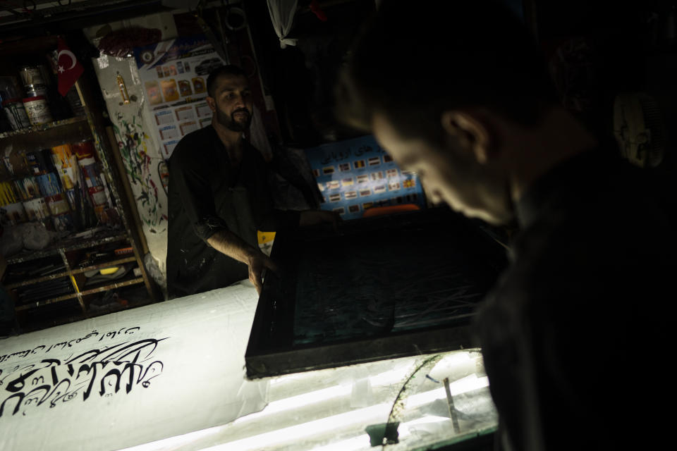 Workers hand print Taliban flags in a small workshop in Kabul's Jawid market, Afghanistan, Sunday, Sept. 12, 2021. The flag shop, tucked away in the courtyard of a Kabul market, has documented Afghanistan’s turbulent history over the decades with its ever-changing merchandise. Now the shop is filled with white Taliban flags, emblazoned with the Quran's Muslim statement of faith, in black Arabic lettering. (AP Photo/Bernat Armangue)