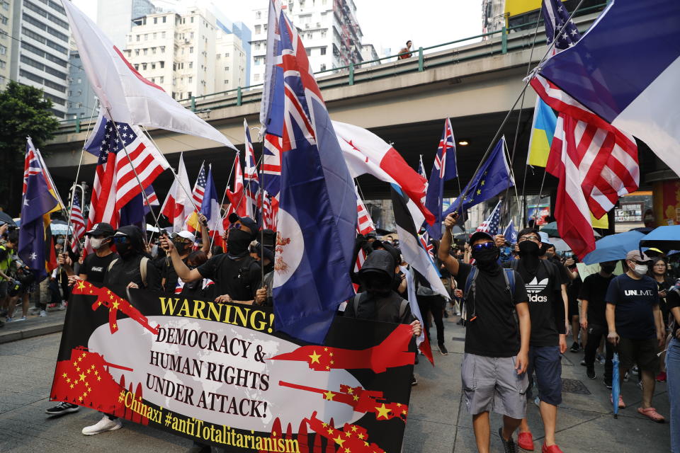 Protestors wave flags of various countries including the U.S. in Hong Kong, Sunday, Sept. 29, 2019. Riot police fired tear gas Sunday after a large crowd of protesters at a Hong Kong shopping district ignored warnings to disperse in a second straight day of clashes, sparking fears of more violence ahead of China's National Day. (AP Photo/Vincent Thian)