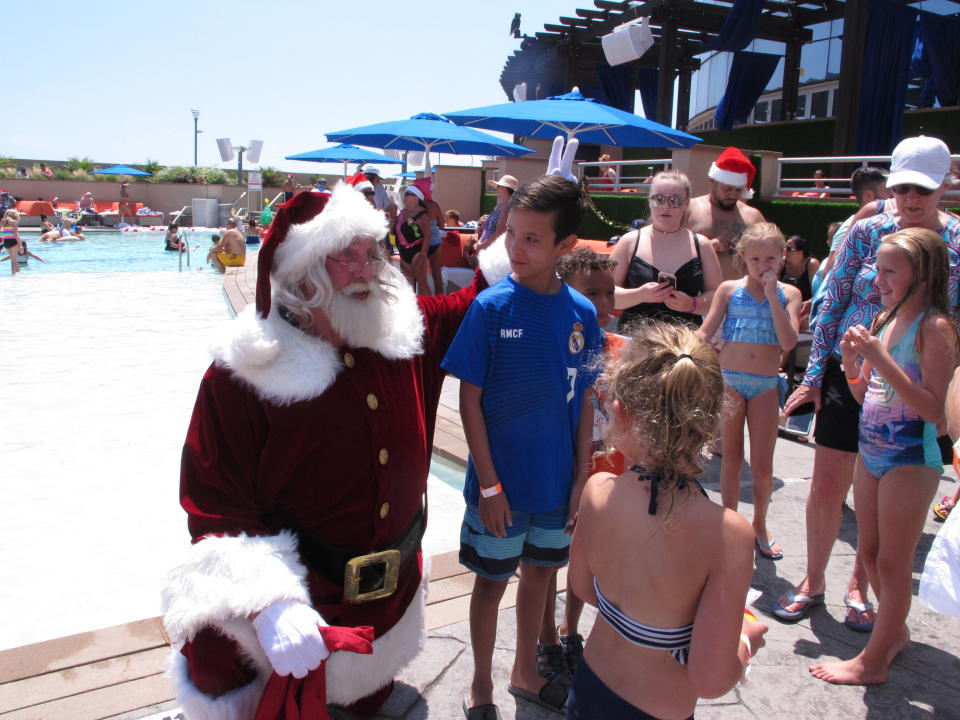 In this July 25, 2019 photo, casino posing for photos with Santa at the outdoor pool at the Ocean Casino Resort in Atlantic City, N.J. Figures released Aug. 14, 2019 by the New Jersey Division of Gaming Enforcement show the casinos took in $323 million, an increase of 7.8% from July 2018. (AP Photo/Wayne Parry)