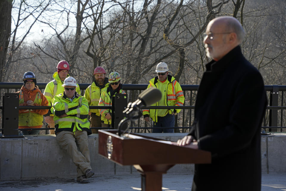 Pennsylvania Governor Tom Wolf, right, gives remarks during a dedication ceremony for the rebuilt Fern Hollow Bridge, as a group of bridge workers listen, in Pittsburgh on Wednesday, Dec. 21, 2022. The original bridge collapsed during a snow storm on Jan. 28, 2022. The collapse of the Fern Hollow Bridge became a symbol of the country's troubled infrastructure. (AP Photo/Gene J. Puskar)