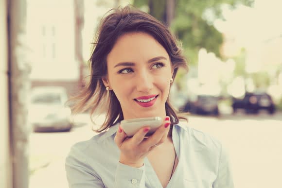 A young woman uses the voice assistant on her smartphone.