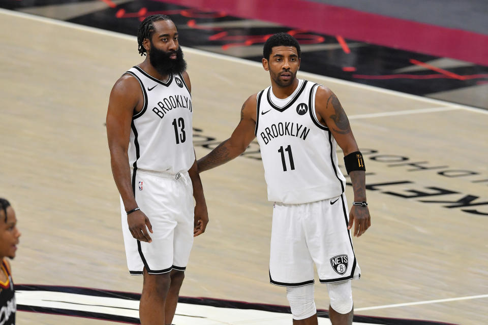 James Harden and Kyrie Irving stand together on the court during a Brooklyn Nets game.