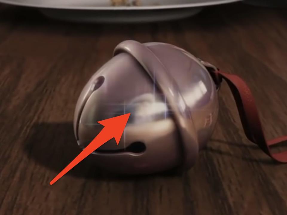 red arrow pointing to santa reflection in the bell from polar express