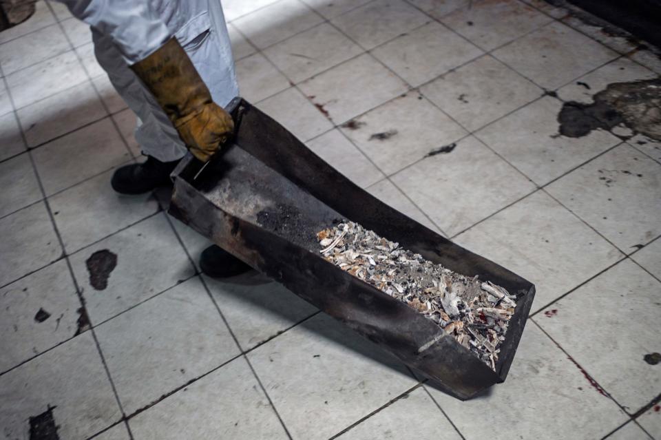 Un trabajador retira las cenizas de una víctima del coronavirus del interior del horno crematorio de Iztapalapa. (Photo by PEDRO PARDO/AFP via Getty Images)