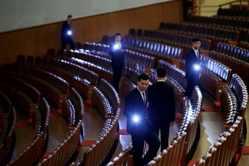 FILE PHOTO: Security personnel check the seats with torches at the end of the opening session of the National People's Congress (NPC) at the Great Hall of the People in Beijing