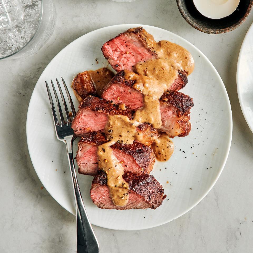 sliced steak with bourbon garlic cream sauce on a white plate