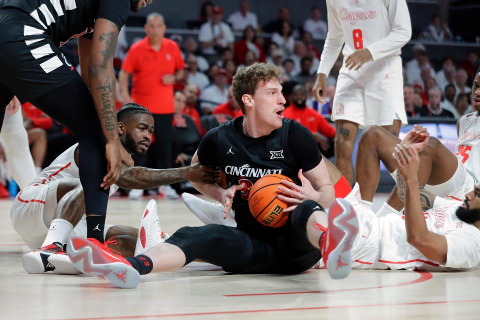 Cincinnati forward Viktor Lakhin, center, looks to pass the ball after recovering a loose rebound between Houston guard Jamal Shead, left, and Houston guard Damian Dunn, right, during the first half of an NCAA college basketball game Tuesday, Feb. 27, 2024, in Houston.
