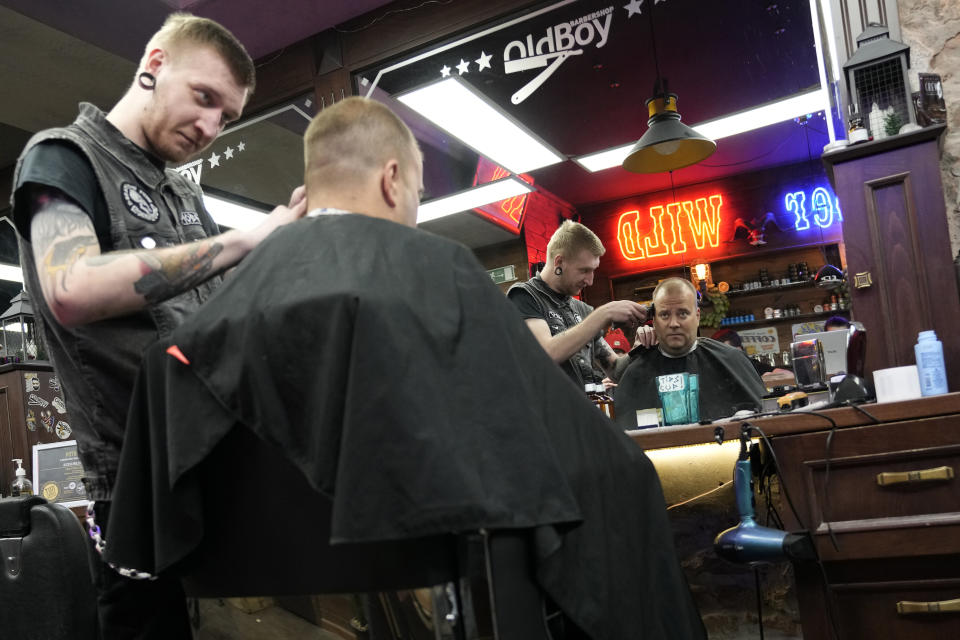 Hairstylist Stanislav Shenkevich, 29, from St. Petersburg gives a customer a haircut at a barbershop in Belgrade, Serbia, Monday, Jan. 16, 2023. A friendly, fellow-Slavic nation, Serbia has welcomed the fleeing Russians who need visas to travel to much richer Western European states. But in Serbia, they have not escaped the long reach of Putin's hardline regime influence.(AP Photo/Darko Vojinovic)