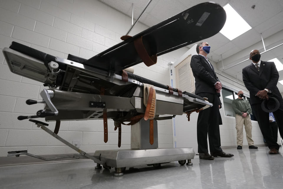 FILE - Virginia Gov. Ralph Northam, left, stands near a gurney with Greensville Correctional Center Warden Larry Edmonds, right, at the correctional center in Jarratt, Va., prior to signing a bill abolishing the state's death penalty, March 24, 2021. The Virginia Department of Corrections has recorded audio of at least 30 executions over the last three decades, but it has no plans to release the tapes publicly. The department rejected an Associated Press request under the state's public records law to release the recordings after NPR obtained and reported on four of them. They offer a rare glimpse into executions. (AP Photo/Steve Helber, File)