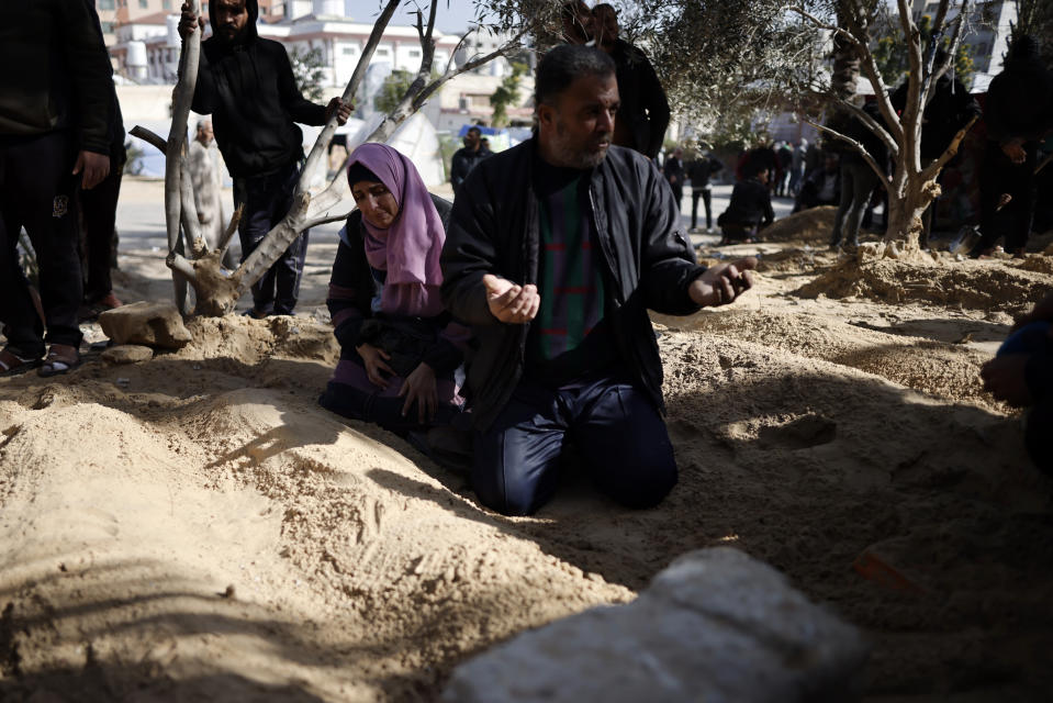 Palestinians mourn their relatives who were killed in the Israeli bombardment of the Gaza Strip, over their graves at the Nasser hospital in Khan Younis, Southern Gaza Strip, Monday, Jan. 22, 2024. (AP Photo/Mohammed Dahman)