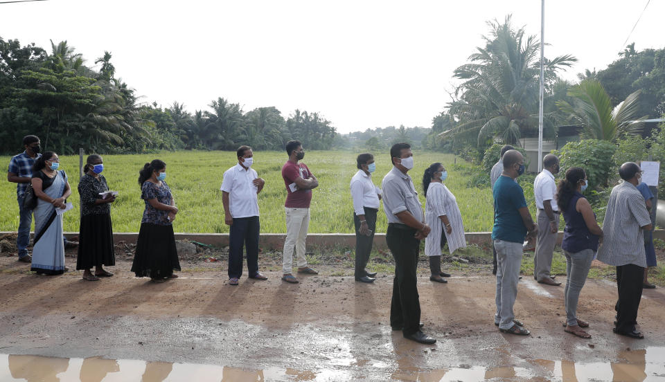 Sri Lankans stand in a queue outside a polling station in Colombo, Sri Lanka, Wednesday, Aug. 5, 2020. Sri Lankans started voting Wednesday to elect a new Parliament that is expected to give strong support to the powerful and popular Rajapaksa brothers. (AP Photo/Eranga Jayawardena)