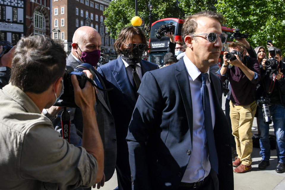 Johnny Depp, center, wearing a protective mask arrives at the Royal Court of Justice, in London, Tuesday, July 7, 2020. Johnny Depp is suing a tabloid newspaper for libel over an article that branded him a "wife beater." On Tuesday, a judge at the High Court is due to begin hearing Depp's claim against The Sun's publisher, News Group Newspapers, and its executive editor, Dan Wootton, over the 2018 story alleging he was violent and abusive to then-wife Amber Heard. Depp strongly denies the claim. (AP Photo/Alberto Pezzali)