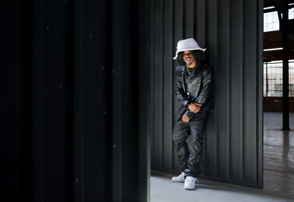 man wearing white bucket hat standing in all black against a black wall