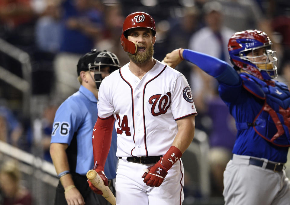 Washington Nationals' Bryce Harper reacts after he was called out on strikes during the 10th inning of a baseball game against the Chicago Cubs, Thursday, Sept. 6, 2018, in Washington. The Cubs won 6-4 in extra innings. Also seen is home plate umpire Mike Muchlinski (76) and Cubs catcher Victor Caratini, right. (AP Photo/Nick Wass)