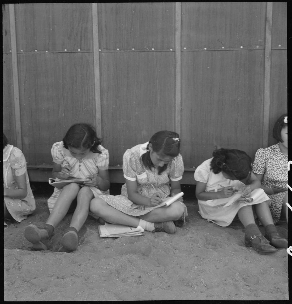 Japanese American children doing school work on dirt ground