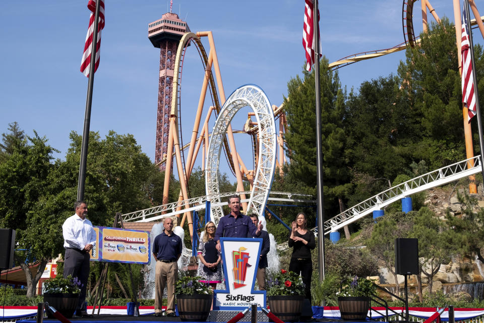 California Governor Gavin Newsom, center, welcomes the public to Six Flags Magic Mountain in Santa Clarita, Calif., on Wednesday, June 16, 2021. In the background are, Don McCoy, from left, President of Six Flags Magic Mountain, Michael Spanos, President of Six Flags, Los Angeles County Supervisor Kathryn Barger and state Sen. Henry Stern. Newsom continued his tour of the state after lifting most COVID-19 restrictions Tuesday. (David Crane/The Orange County Register via AP)