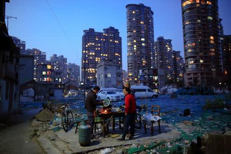 Jiang Wei cooks dinner outside a six-square-meter house he rents with a friend, at Guangfuli neighbourhood in Shanghai, China, March 28, 2016. REUTERS/Aly Song