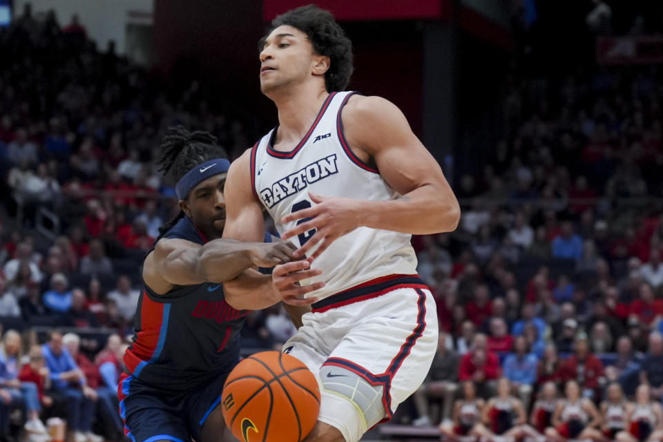 Duquesne guard Jimmy Clark III, back, knocks the ball away from Dayton forward Nate Santos during the first half of an NCAA college basketball game, Tuesday, Feb. 13, 2024, in Dayton, Ohio. (AP Photo/Aaron Doster)