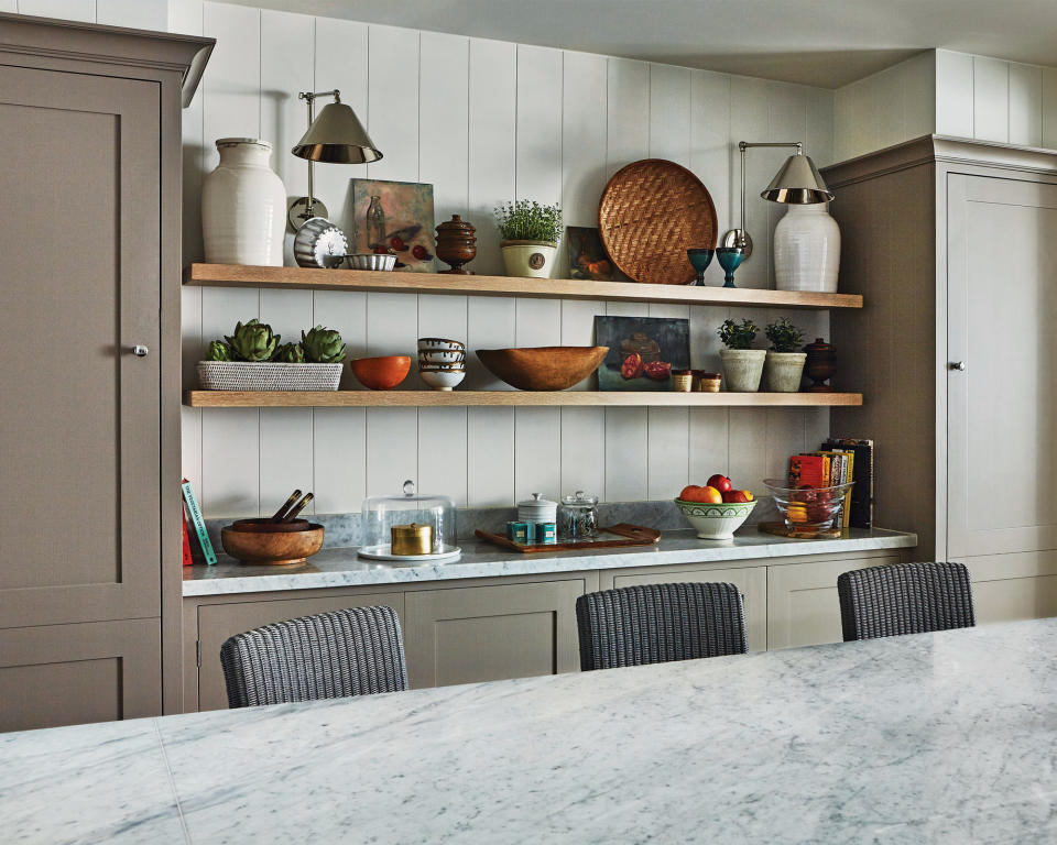 View across the marble topped kitchen island with shelves in the background with dishes and baskets.