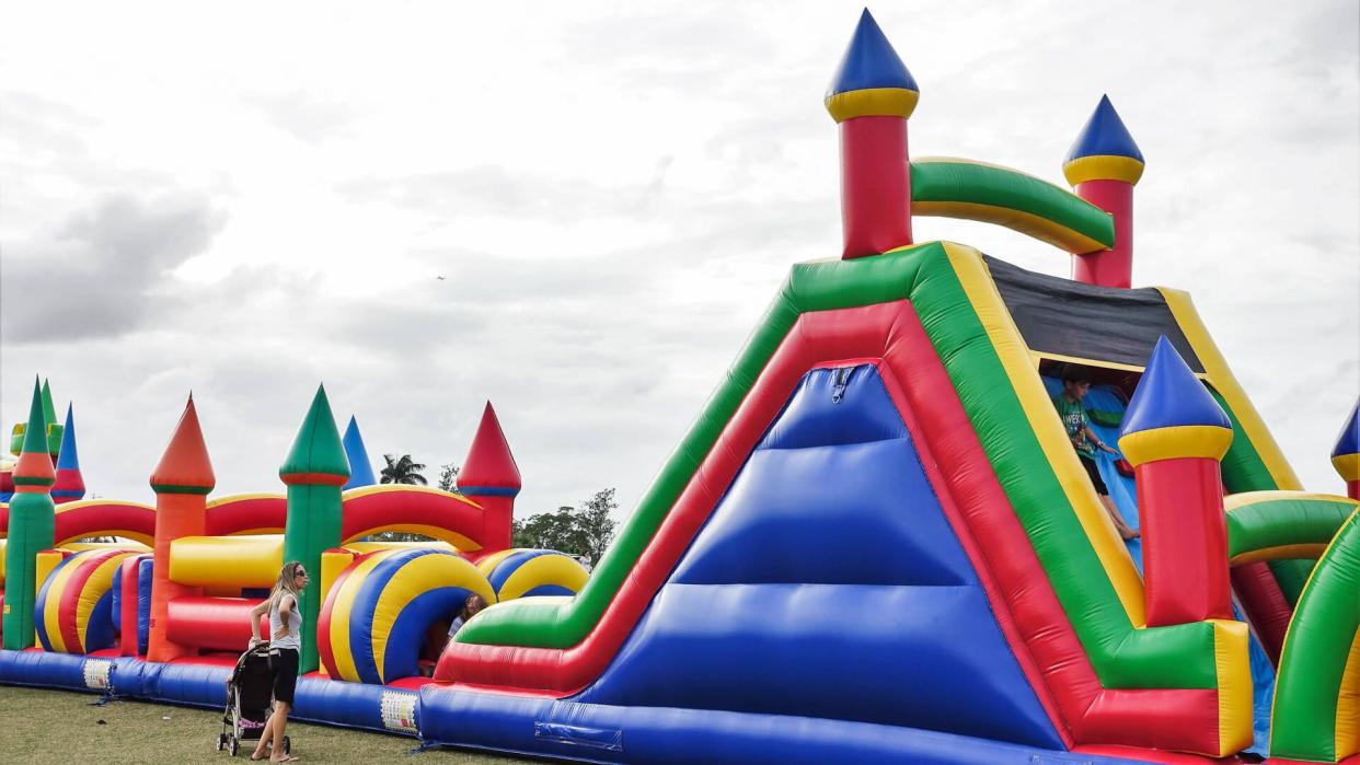 A row of colorful bounce houses are located on a grassy field at a public park in suburban Palm Beach County, FL.