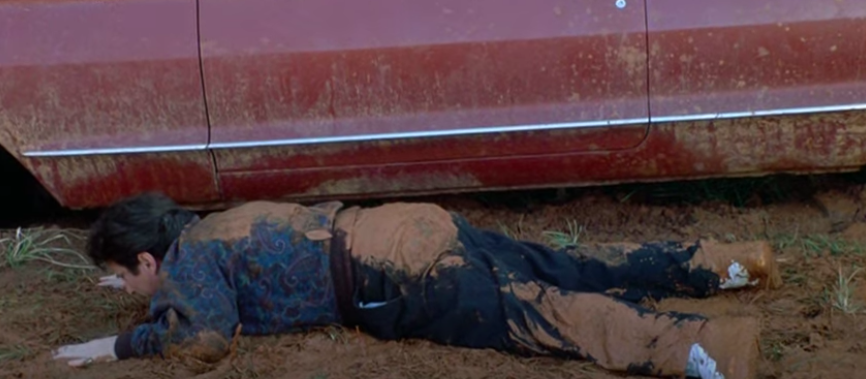 A man falls out of his car and into mud