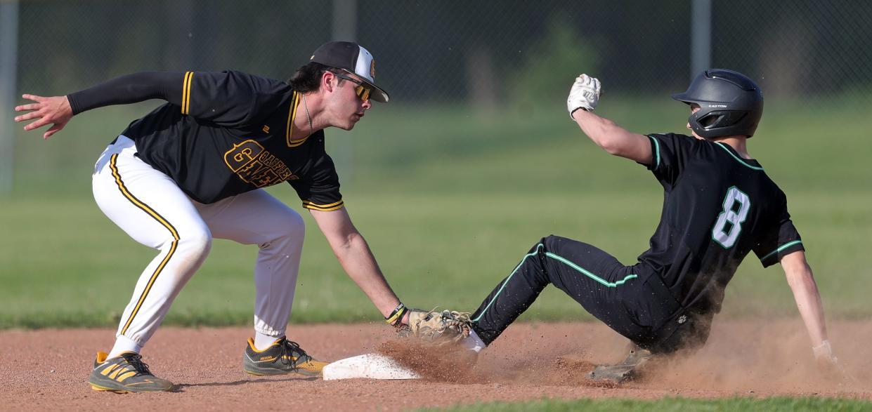 Garfield shortstop Eric Geddes, left, fails to make the tag in time as Mogadore baserunner Devin Graham steals second base during the third inning of a high school baseball game, Wednesday, May 1, 2024, in Garrettsville, Ohio.