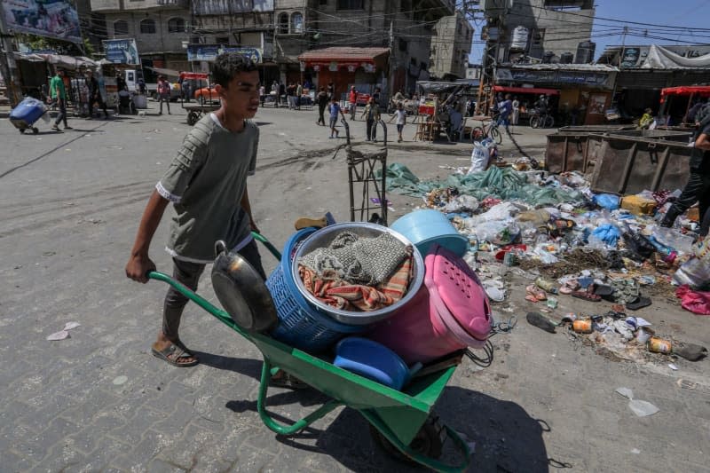 A Palestinian boy pushes a wheelbarrow loaded with personal belongings as he flees following Israeli airstrikes on Al-Geneina and Al-Salam neighbourhoods. Abed Rahim Khatib/dpa